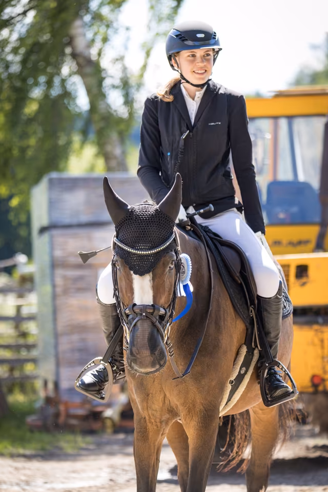 Feline Rautmann lächelnd auf einem Pony mit Schleife